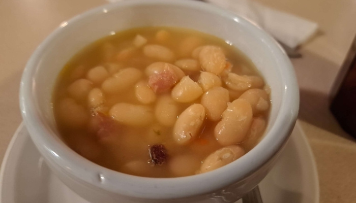 A white bowl of bean soup from JC's Country Diner Restaurant Elwood Utah, hearty and inviting.