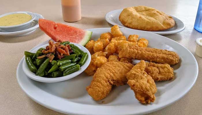 A plate at JC's Country Diner Restaurant Elwood Utah: fried chicken, tots, beans, melon, biscuit.
