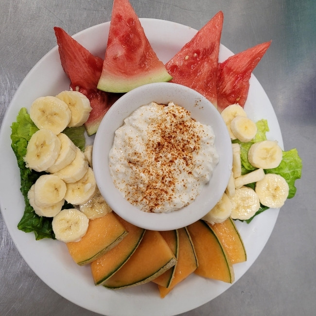 A plate at JC's Country Diner Restaurant Elwood Utah with watermelon, banana, cantaloupe, and dip.