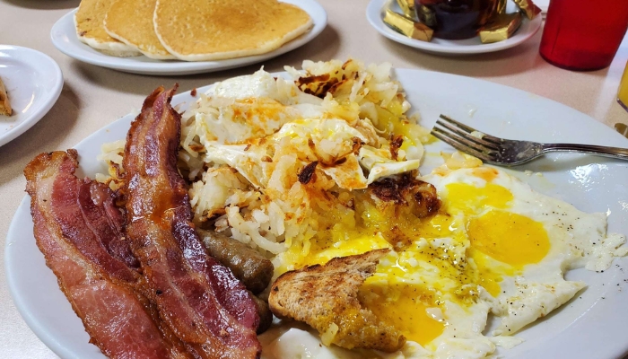 A plate at JC's Country Diner Restaurant Elwood Utah with bacon, eggs, pancakes, and more.