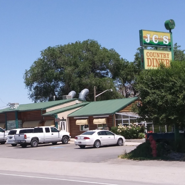 JC's Country Diner Restaurant in Elwood, Utah, with green roof, parked cars, and a large tree.