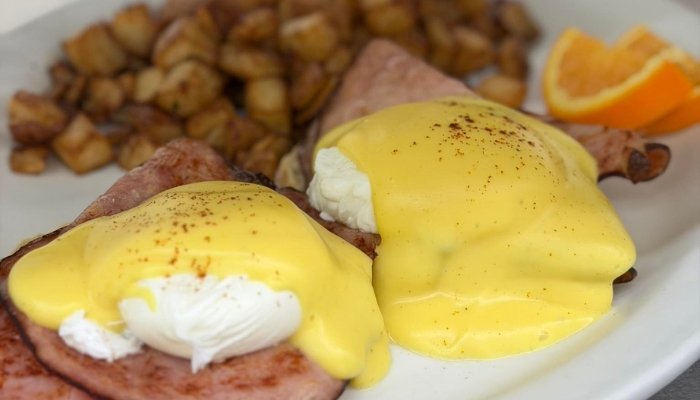 Eggs Benedict with ham at JC's Country Diner Restaurant Elwood Utah, served with potatoes and orange.
