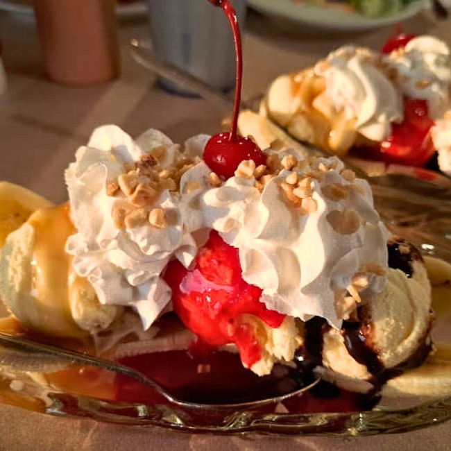 A banana split at JC's Country Diner Restaurant Elwood Utah, topped with cream, nuts, and a cherry.